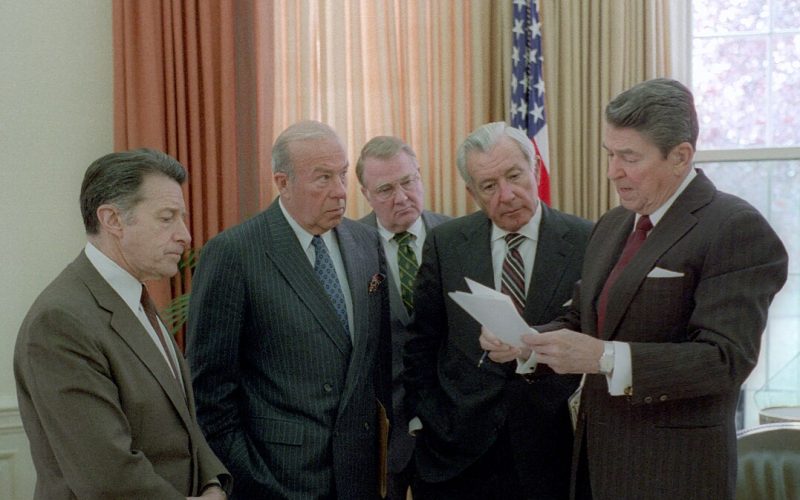 1077px-President_Ronald_Reagan_meets_with_aides_on_Iran-Contra_(cropped) By Series: Reagan White House Photographs, 1/20/1981 - 1/20/1989Collection: White House Photographic Collection, 1/20/1981 - 1/20/1989 - https://catalog.archives.gov/id/75855169, Public Domain, https://commons.wikimedia.org/w/index.php?curid=160141109